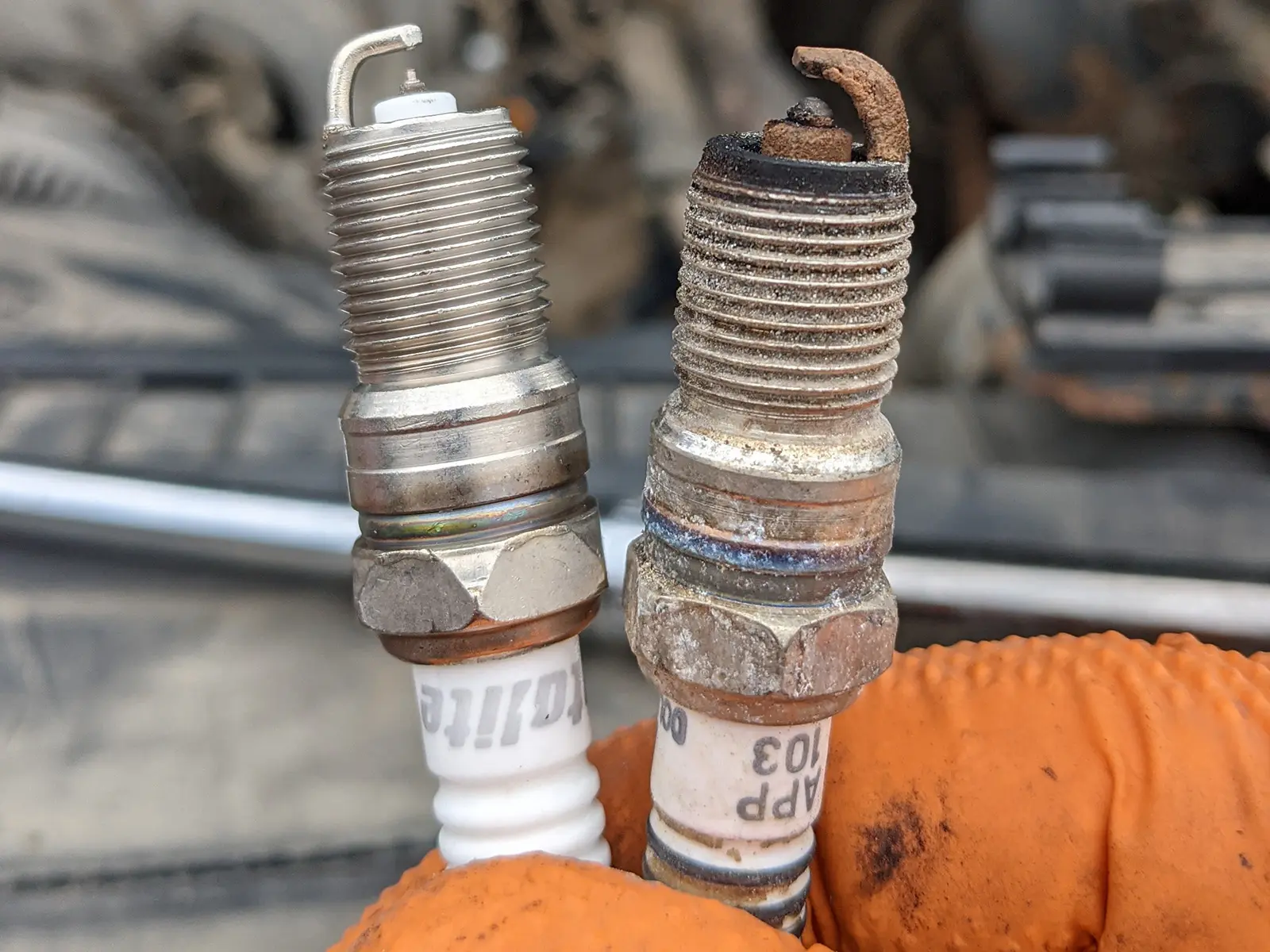 Worn spark plug compared with a new spark plug during mobile auto repair in Frisco, Texas